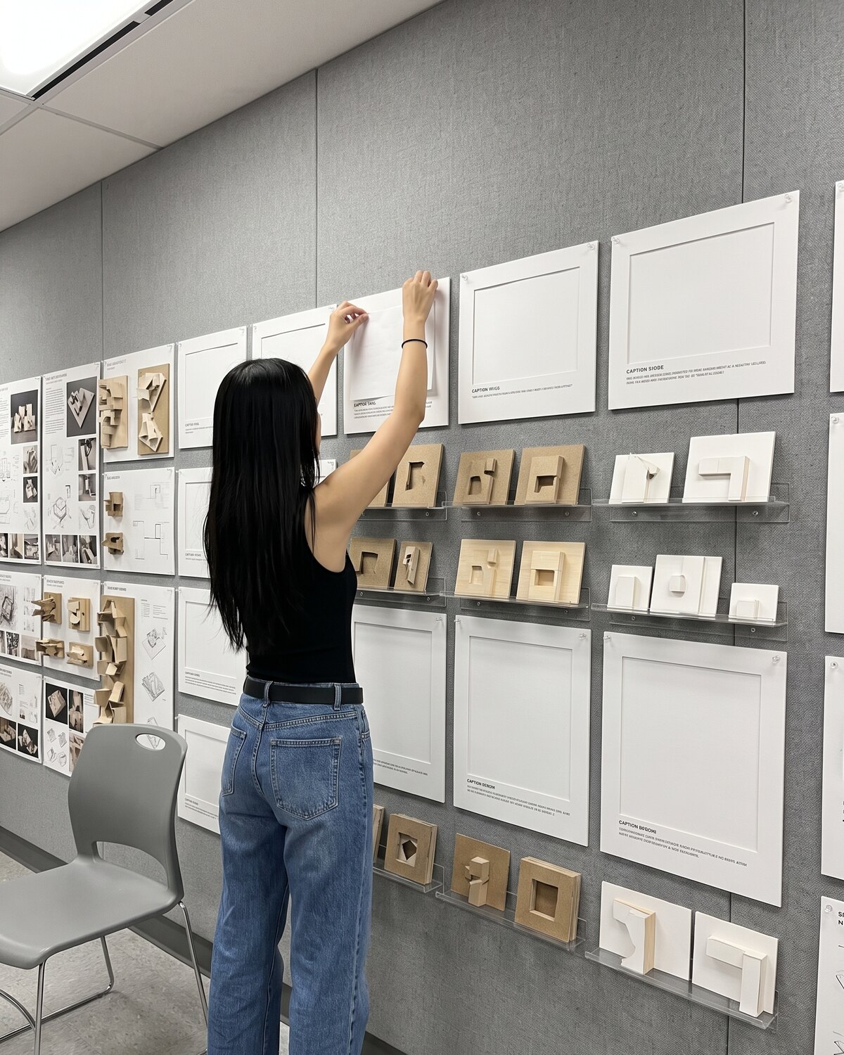 Sheets and study models pinned to a review wall, one being put up