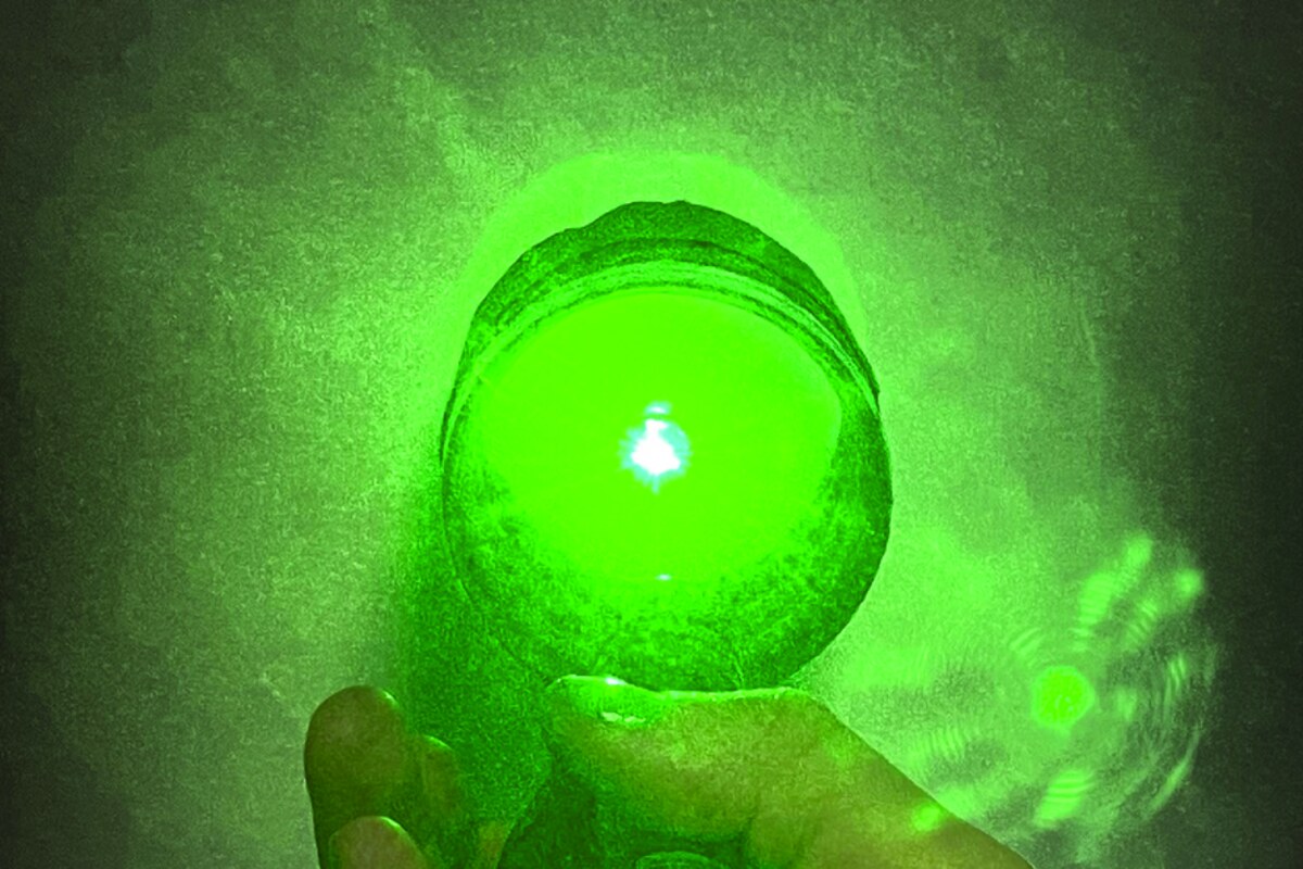 A hand holding a glowing green sphere lit from within